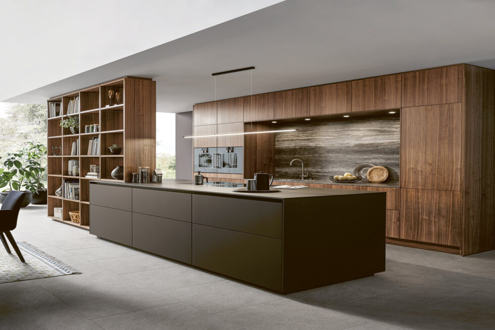 Moderne Outdoor-Küche mit orangefarbenen Fronten, Grill und großem Esstisch im grünen Garten auf Mallorca