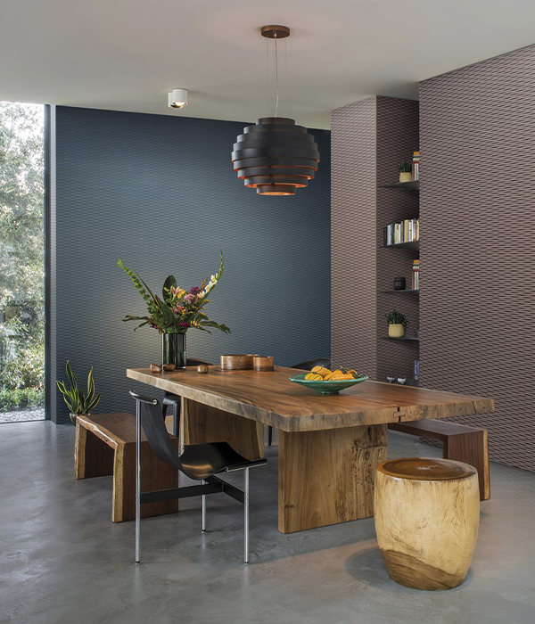 Essbereich mit großem Holztisch, Bank, Stuhl, Blumenarrangement und moderner Pendelleuchte vor strukturierter Wand