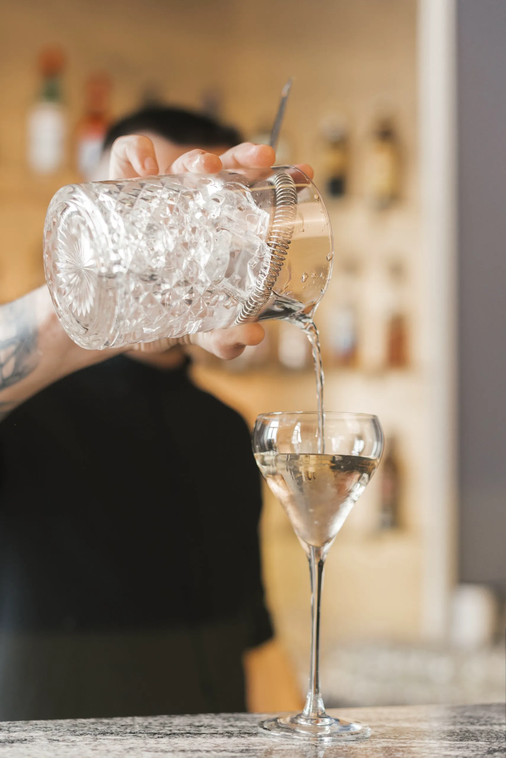 Barkeeper giesst Gin-Cocktail aus Kristallmixglas in eine Coupe-Schale auf Mallorca