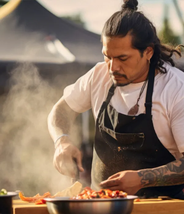 Koch mit Dutt grillt Gemuese am Outdoor-Grill bei Live-Cooking-Event auf Mallorca