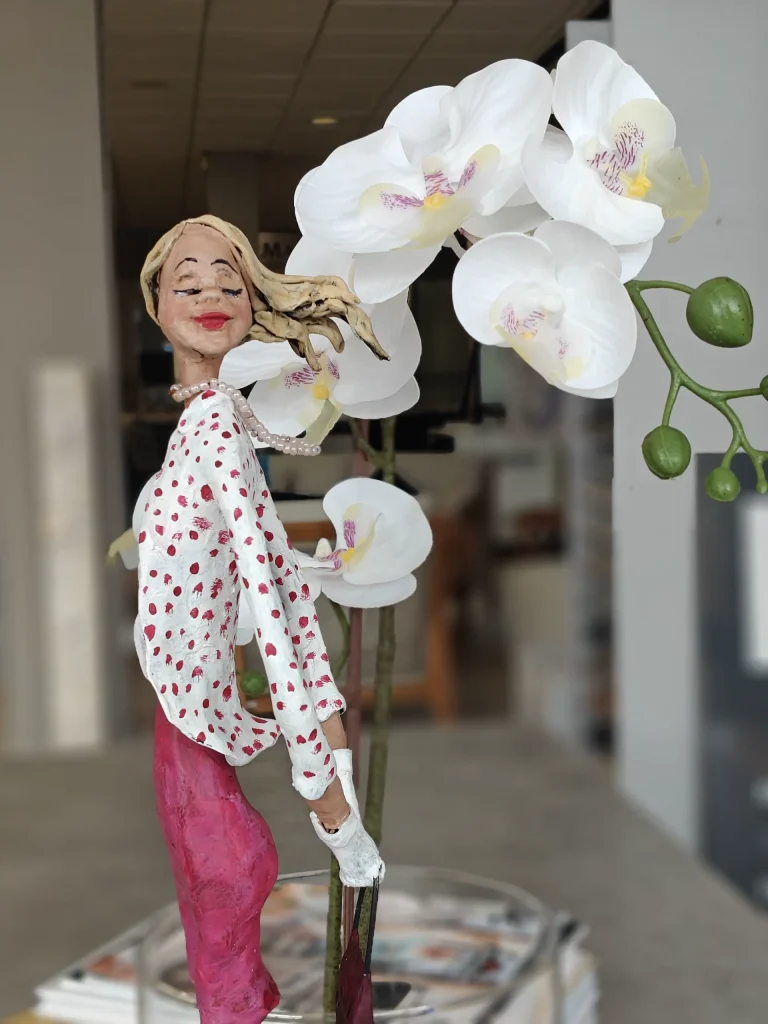 Elegante Frauenskulptur in gepunkteter Bluse neben weissen Orchideen – Regine Kielmann, Mallorca