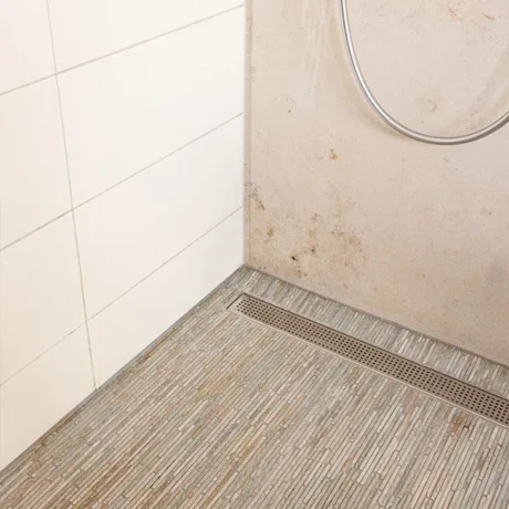Bodengleiche Dusche mit Naturstein-Mosaikboden und elegantem Linienablauf auf Mallorca